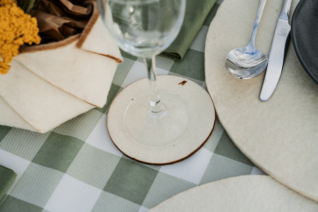 Natural wool coasters on rustic outdoor table in rural setting, sustainable tableware for slow living and restaurants