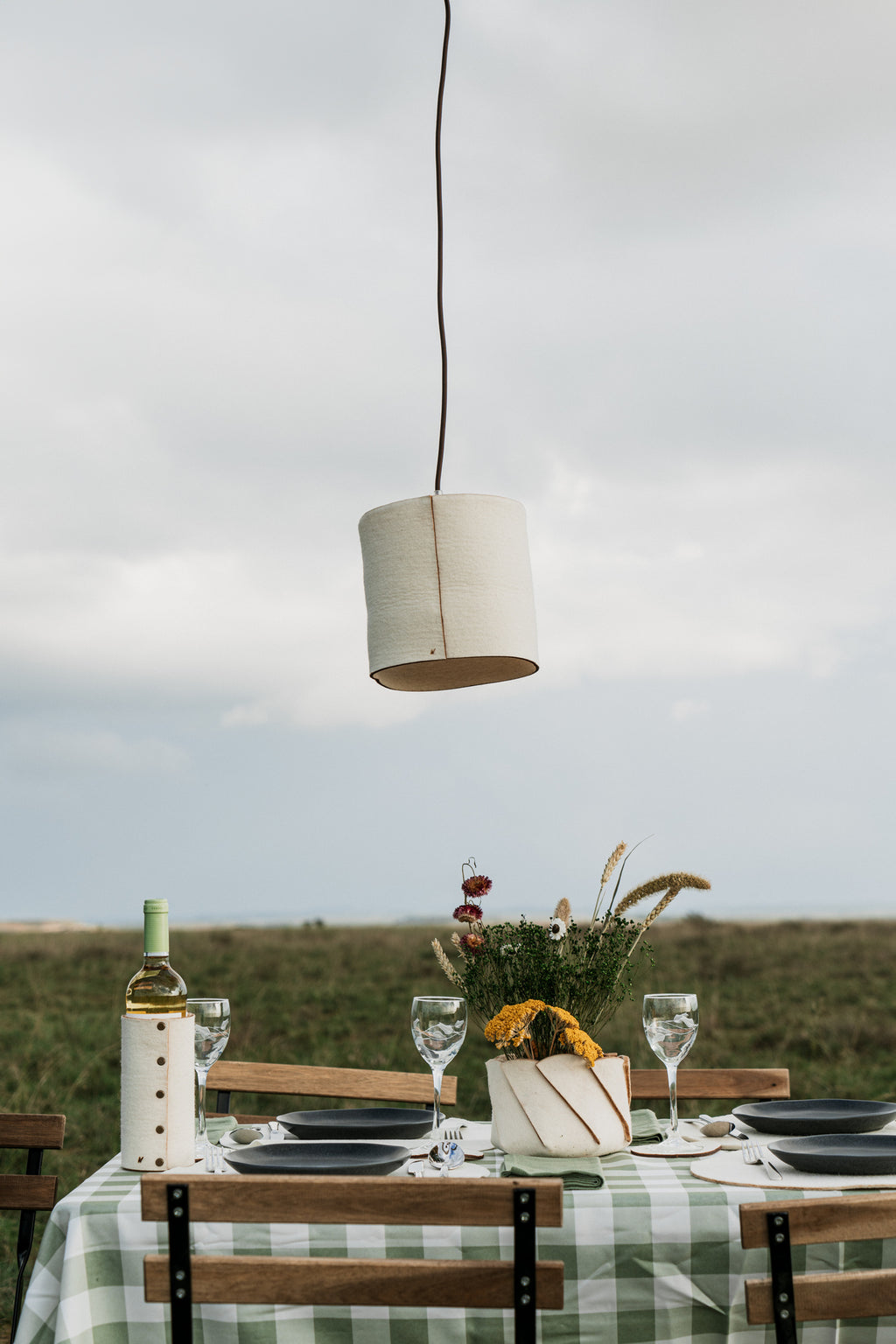 Rustic outdoor dining setting with wool lampshade, natural lighting for slow living homes and hospitality spaces